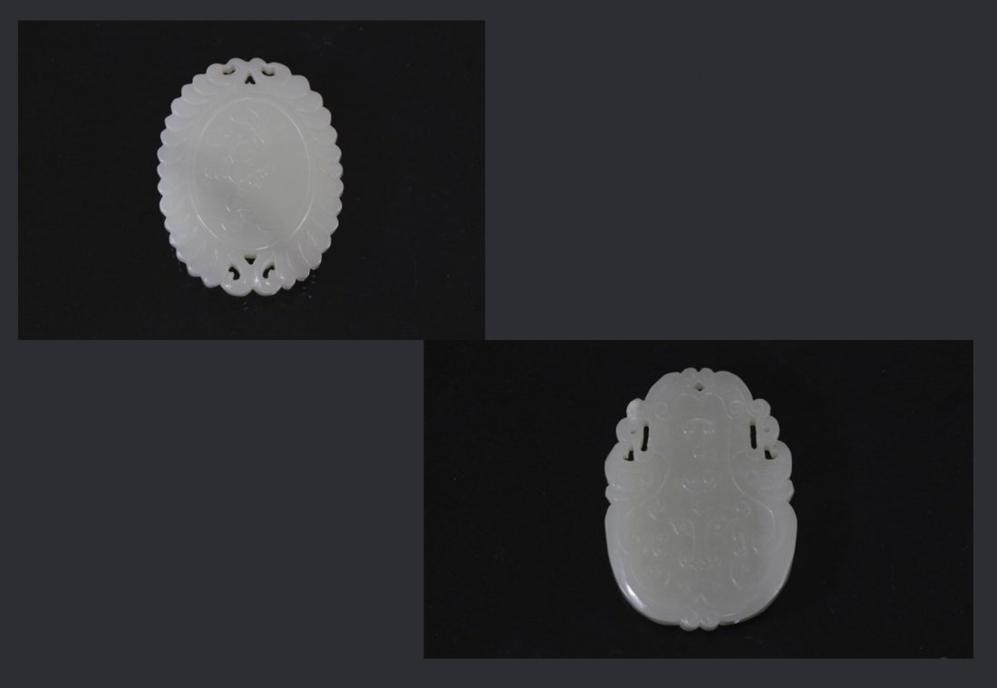 Two Jade Pendants with Chinese carving: A delicate white jade pendant, of oval shape, carved with ox face in shallow relief on both sides, with intricate openwork and detailing on rim. Length 1.25" Height 2".A white jade pendant, of oval sh