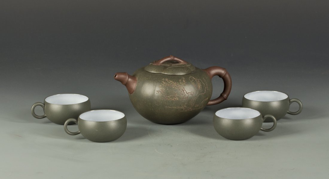 One Zisha Teapot and Four Cup Mark with Zu De: One Zisha Teapot and Four Cup. Ben Shan Green Zisha clay. Inside of cup is sealed by white color glaze. Mark with Zu De. Length 7.25" Width 5" Height 3.75" Length 3.5" Width 2.5" Height 1.5"