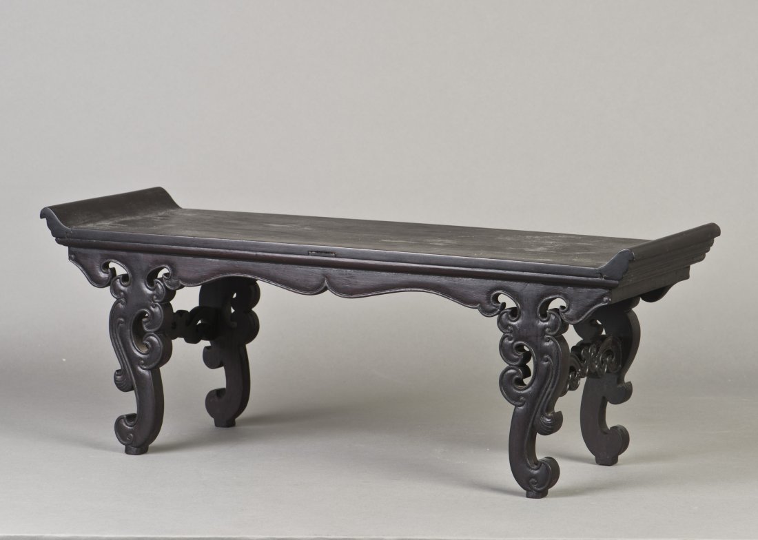 A SMALL RECTANGULAR ZITAN ALTAR TABLE: The top panel supported on four legs below the apron, with beading to the edges, scroll-form spandrels and stretchers extended to scrolling cloud form legs, terminating in scroll-form feet. Height 7.7