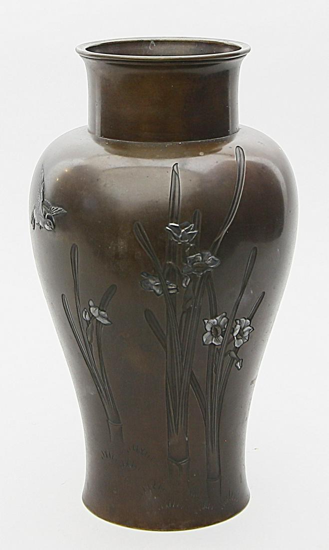 Vase.: Braun patinierte Bronze. Schauseitig mit getriebenem Blumendekor, reliefiertem Vogel und Blüten mit Silber- oder Zinneinlagen. Kratzer. Boden mit kalligraphischer Marke, Japan, späte Meiji-P