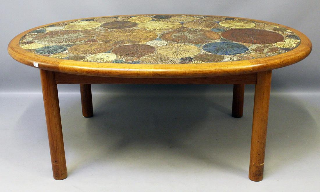 Poulsen, Tue (geb. 1939 Dänemark): Couchtisch. Teakholzgestell, ovale Platte mit farbig reliefiertem Keramikmosaik. Gebrauchsspuren. Unterseite mit Herstelleretikett HASLEV (Möbelfarbrik) Made in Denmark, 60er Jahre. 56x 134x 98 c