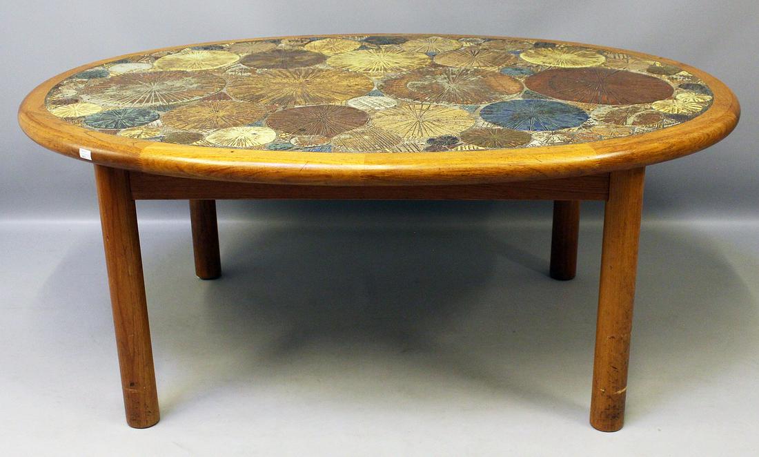 Poulsen, Tue (geb. 1939 Dänemark): Couchtisch. Teakholzgestell, ovale Platte mit farbig reliefiertem Keramikmosaik. Gebrauchsspuren. Unterseite mit Herstelleretikett HASLEV (Möbelfarbrik) Made in Denmark, 60er Jahre. 56x 134x 98 c