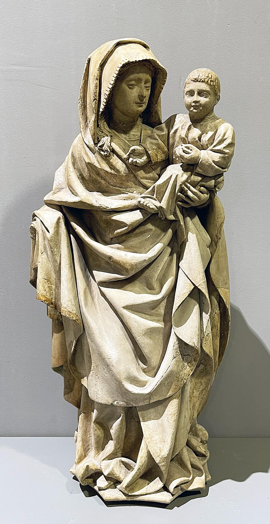 Unbekannter Bildhauer des Barock (wohl 17. Jh. oder: Stehende Madonna mit Kind. Wohl Kalkstein, mit Gips modelliert, hellgraue Fassung (erg.), offene Rückseite mit eingelassener Öse aus Eisen. Fehlende Hand, best./rest. H. 74 cm.