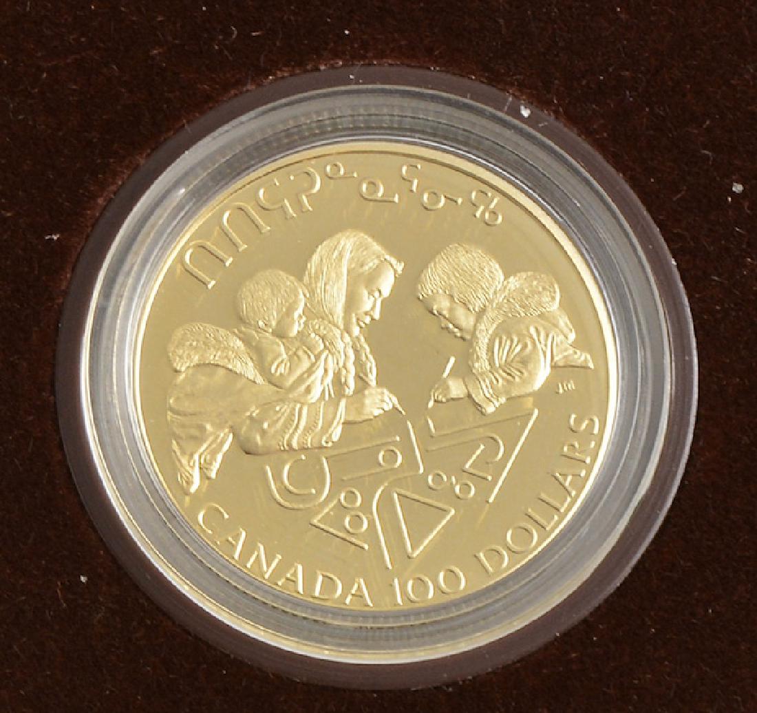 CANADIAN 100$ - 14K GOLD AND SILVER - 1990: Canadian 14K gold and silver (58.33% gold and 41.67 silver) 100$ coin from 1990, the obverse with the face Elizabeth II, the reverse with the design of artist John Mardon depicting an Inuit writing sy