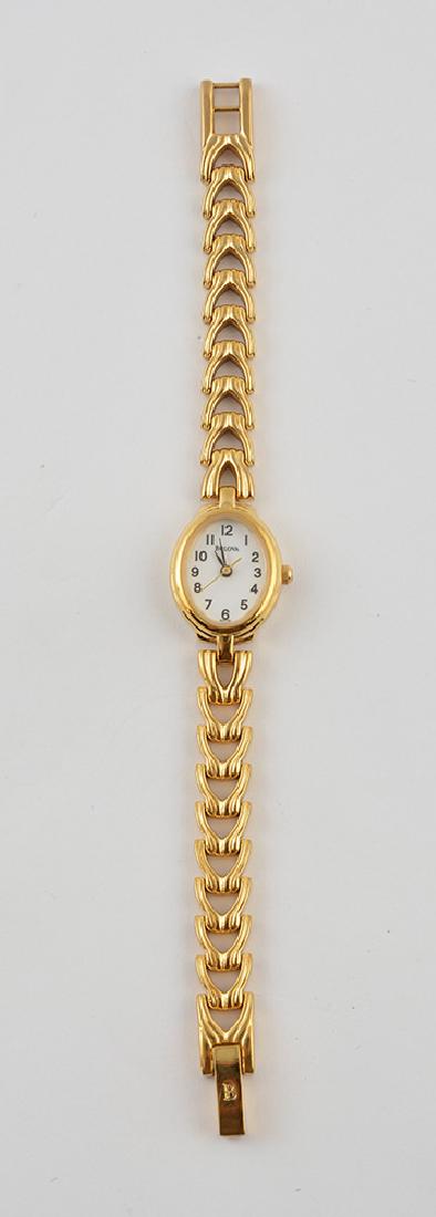 BULOVA: Gilt metal and stainless steel woman's wristwatch, white dial, numbered index, quartz movement. Signed "Bulova" on the dial. Weight: 22.2g.