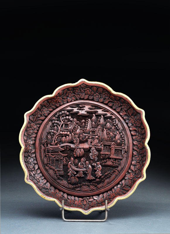 CINNABAR LACQUER CHARGER MARKED QIANLONG: A FINE CINNABAR LACQUER CHARGER MARKED QIANLONG CHINE 19TH CENTURY the cavetto adorned with immortals (xianren), attendants, pavilions, rocks and pine trees, the wing with flowered plum branches (mei