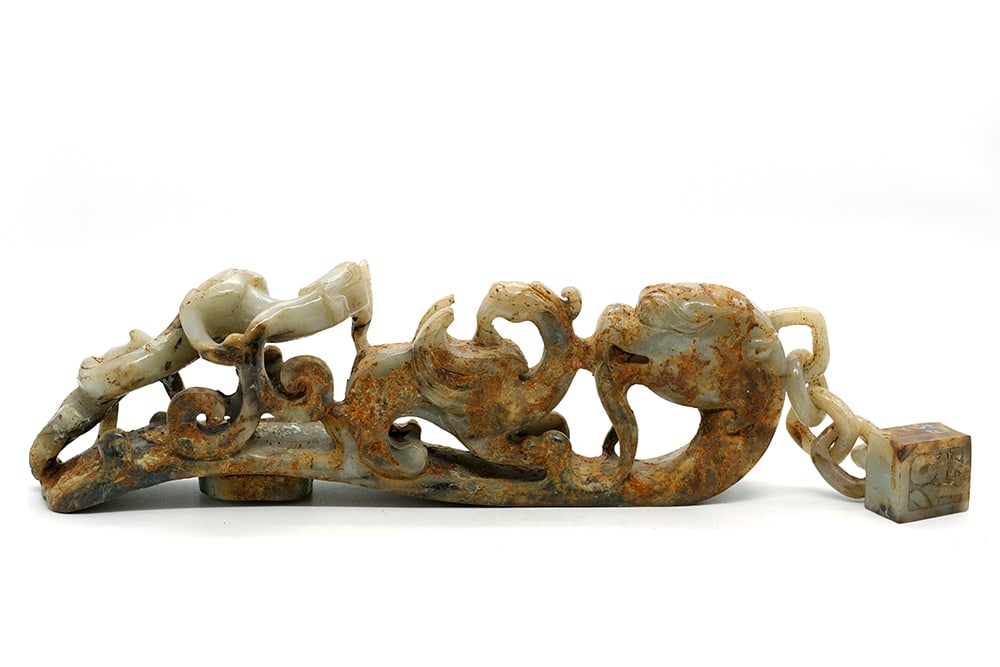 CHIMÈRE ET SCEAU CHINOIS EN SERPENTINE / CHINESE SERPENTINE FIBULA CHIMERA AND SEAL: Description française: CHINE Fibule en serpentine partiellement calcifié, représentant un chilong et une chimère ailée, l’extrémité formée par une tê