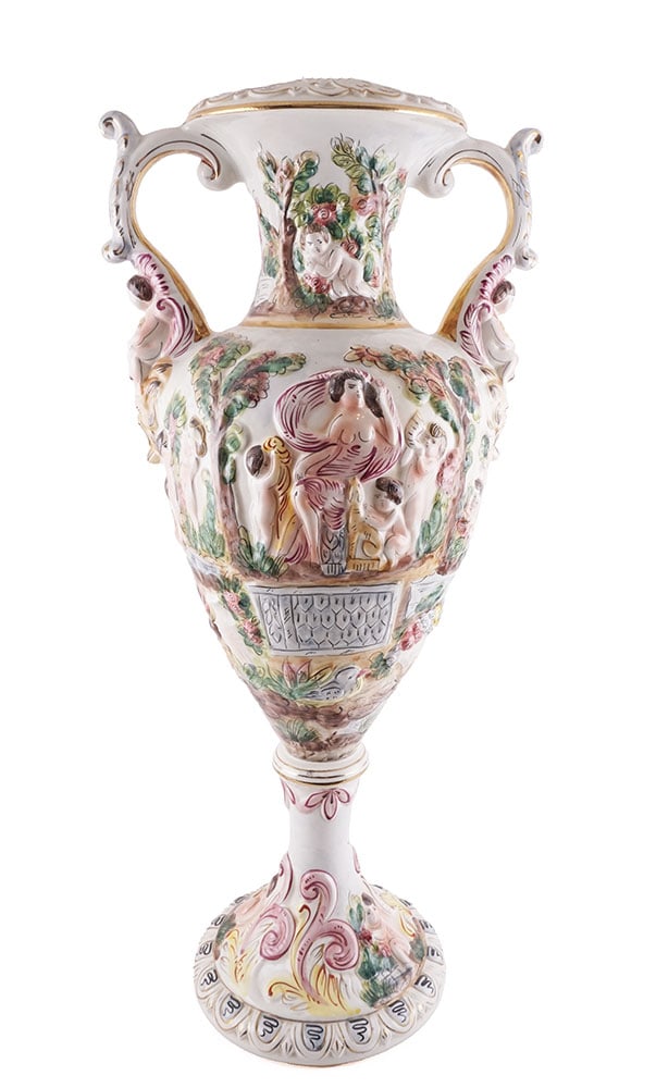 CAPODIMONTE: Description française: CAPODIMONTE Vase sur piédouche en porcelaine émaillée Capodimonte, deux anses en forme de volutes sur lesquelles se reposent deux putti, décor en bas-re