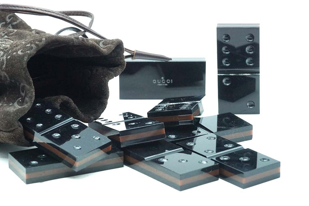 GUCCI - DOMINOS: Description française: GUCCI - DOMINOS Rare jeu de dominos Gucci, dans leur sacoche frappée du monogramme de la marque. Pièces noires polies et mention "Gucci". English Description: