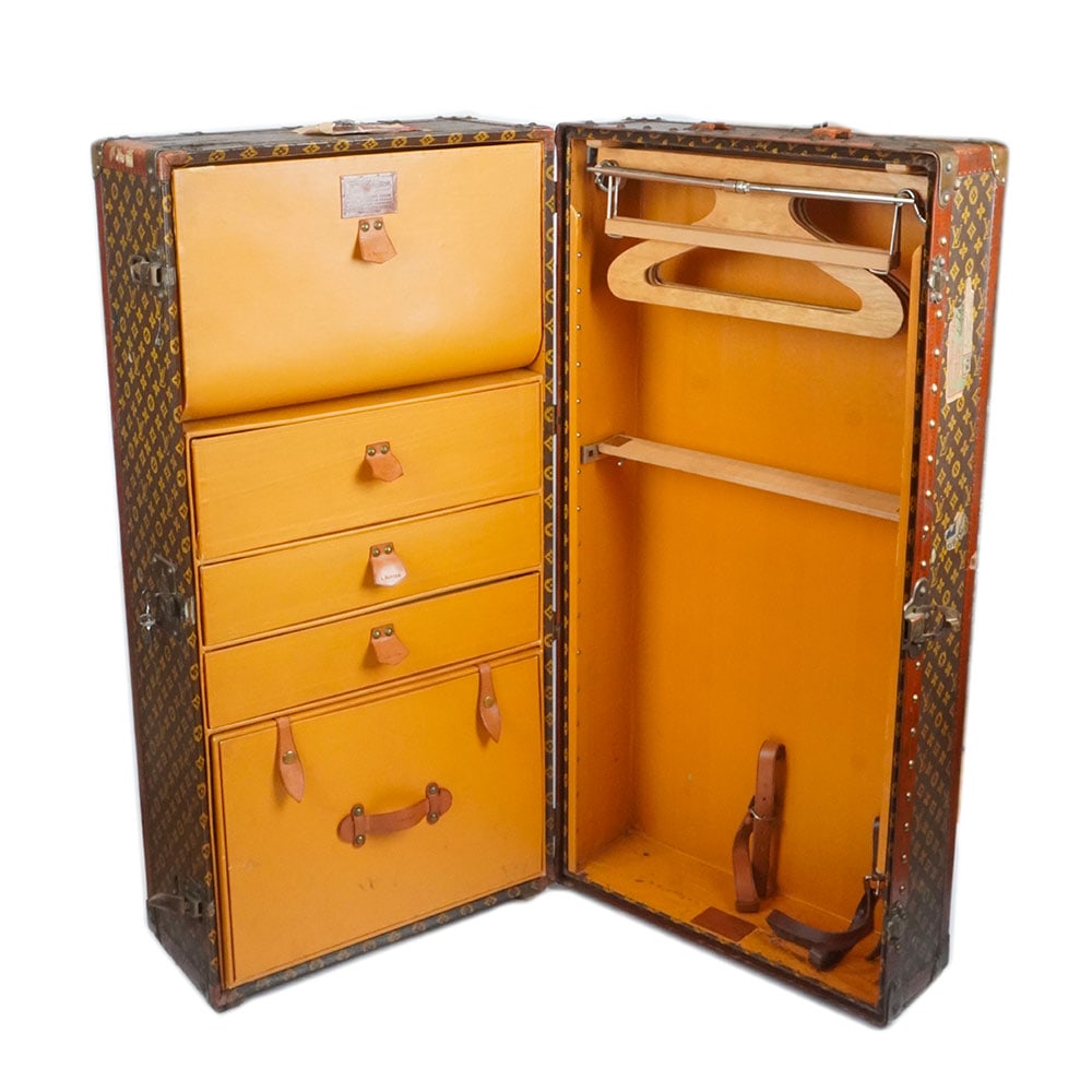 MALLE LOUIS VUITTON / WARDROBE LOUIS VUITTON: Description française: MALLE LOUIS VUITTON / WARDROBE LOUIS VUITTON Malle garde-robe Louis Vuitton en toile monogrammée, cuir et finitions en laiton, numéro de série : 760500,