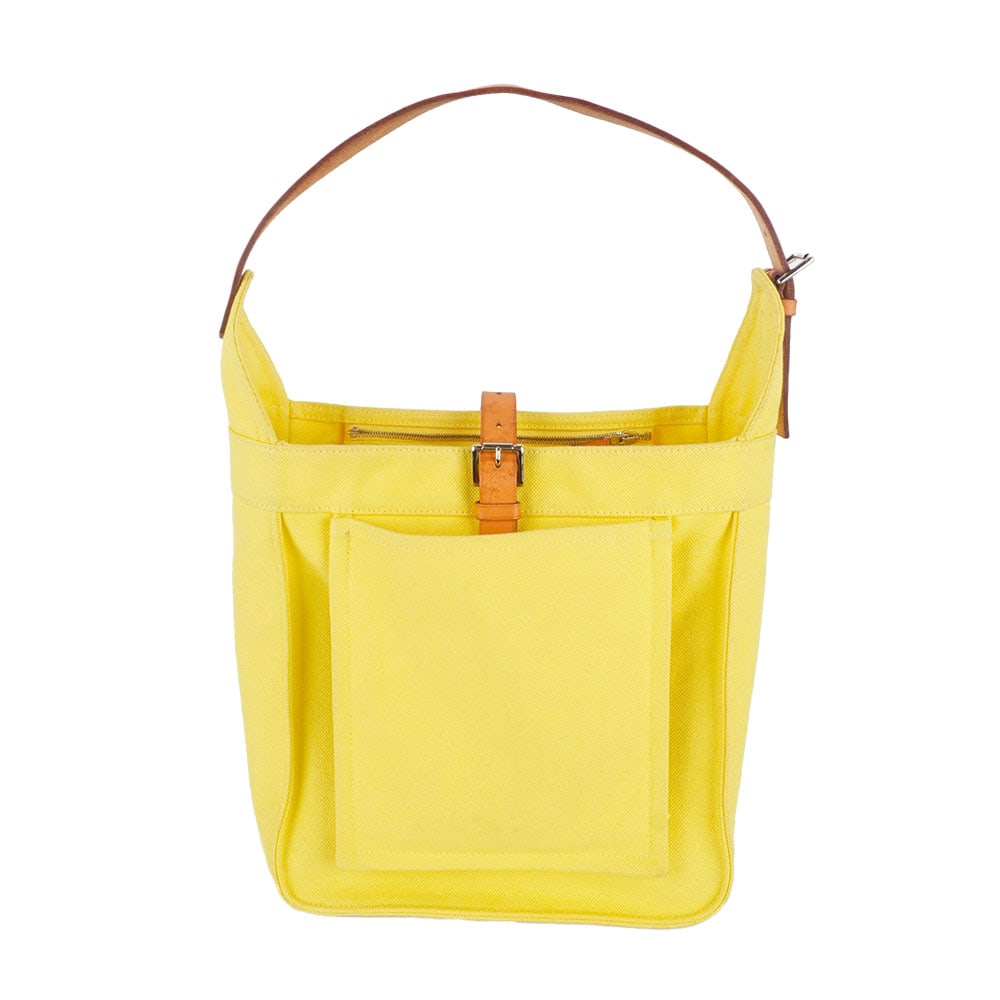 HERMÈS: Description française: HERMÈS Sac Hermès en toile jaune, une anse en cuir naturel pour le porter à l'épaule, une poche ouverte sur le dévant, une poche zippéée 