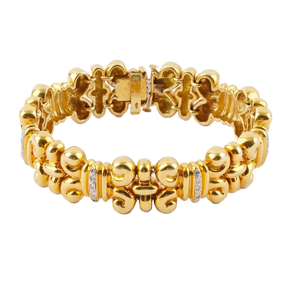 OR 18K / 18K GOLD: Description française: OR 18K / 18K GOLD Bracelet ajouré et articulé en or jaune 18K entrelacé de mallons sertis de diamants. Poids brut: 73.8 g Longueur: 18 cm - 7" Largeur: 1.6