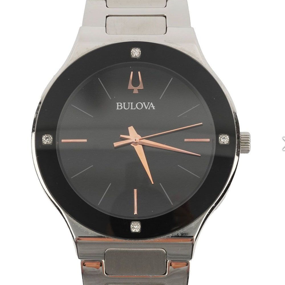 BULOVA: Description française: BULOVA Montre Bulova en acier, boîtier rond de 43 mm environ, cadran noir, index appliqués pour les heures, 4 pierres sur la lunette, mouvement quartz,