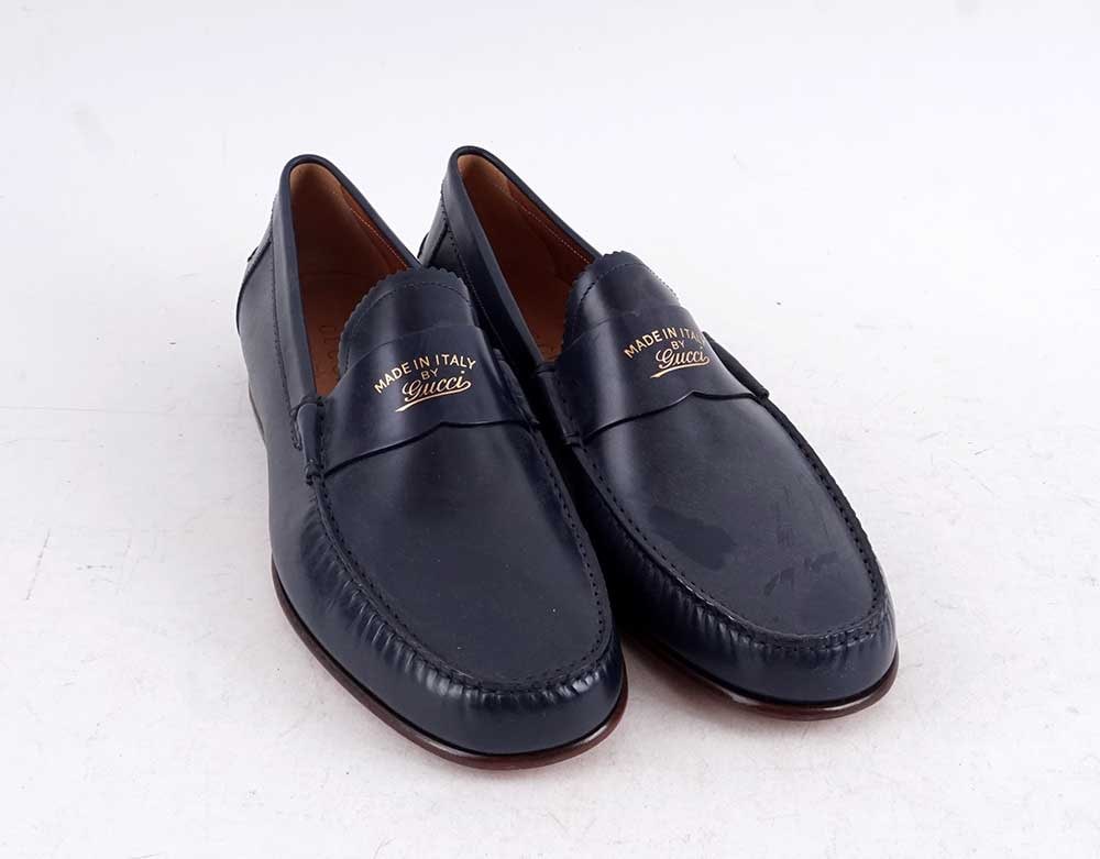 GUCCI: Description française: GUCCI Mocassins de cuir bleu avec inscriptions sur la bride. Taille 8 English Description: GUCCI Blue leather penny loafers with inscription on the strap. Size 8