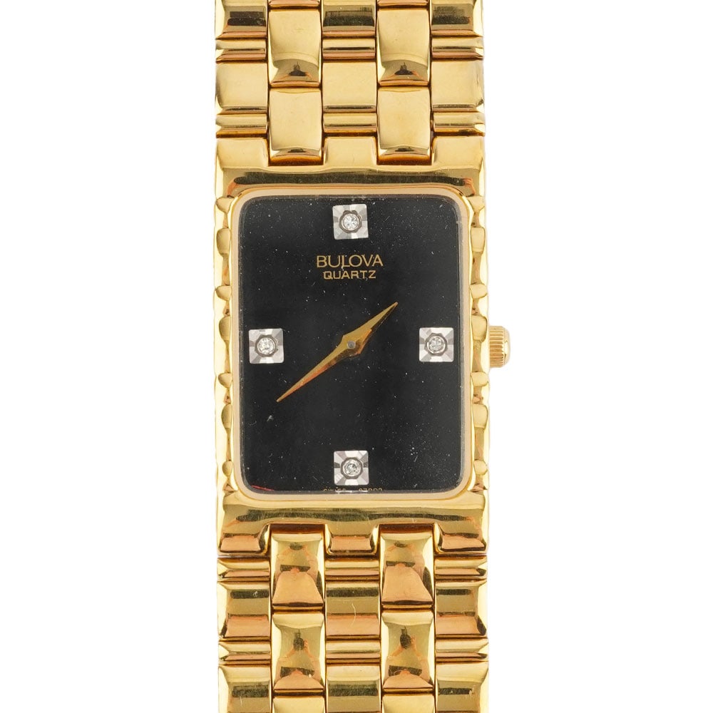 BULOVA: Description française: BULOVA Montre- bracelet Bulova Quartz en métal doré, boîtier rectangulaire de 28 x 22mm, cadran noir, index 4 pierres appliqués pour les heures,