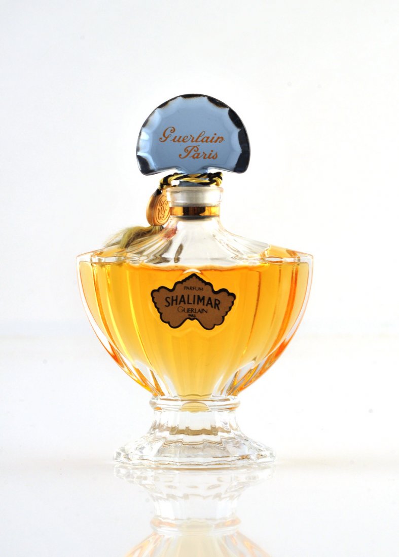 SHALIMAR - GUERLAIN: Transparent pressed molded glass perfume bottle from Guerlain, figuring a ribbed urn on an oval carved base, Bosphore blue tinted and titled glass stopper. Stamped "Parfum Shalimar Guerlain". 5 FL OZ