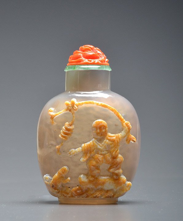 CHALCEDONY AGATE SNUFF BOTTLE: CHALCEDONY AGATE SNUFF BOTTLE carved with a fish on the reverse, the front with a man trying to catch a toad with a string cash, China, QING DYNASTY. Stopper. H: 6cm - 2,25" E : 400 / 500