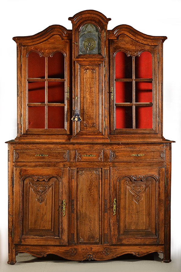 LOUIS XV PERIOD - LIEGE: Louis XV period natural wood buffet, opening by two sculpted swing doors with raie au coeur and volute decor, three belt drawers, Liege. Its is si on top of matching displaycase with central clock, op