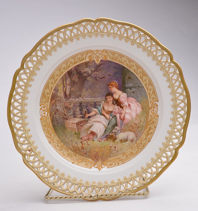 KPM - GERMANY: KPM polychrome porcelain plate with bucolic scene representing two friends, the outline with openworked gilt frieze decor. Germany, 20th Century Stamp on the reverse on the base : The sceptre and the