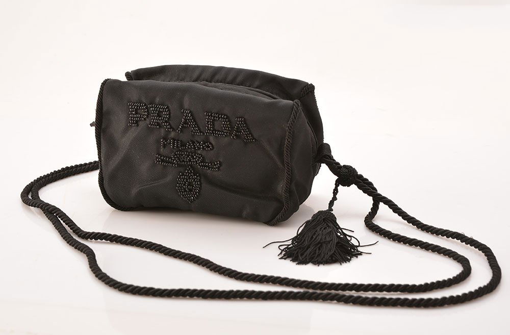 PRADA MILANO - MADE IN ITALY: PRADA MILANO - MADE IN ITALY Black nylon pouch, embroidered logo at the centre, braided cord shoulder strap with pompom, interior composed of a zipped pocket, zipped fastening. H: 9cm - 3.5" L: 15cm -