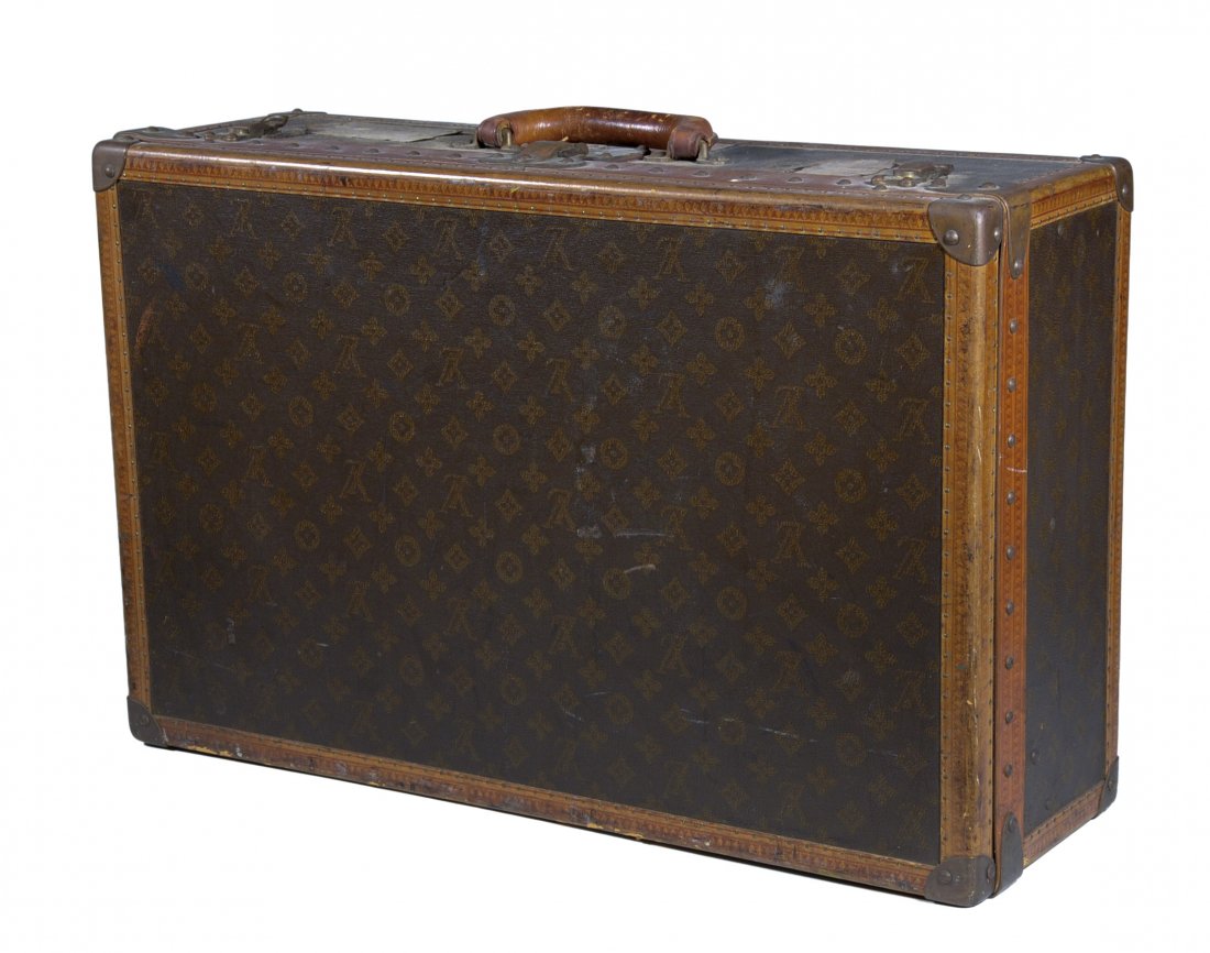 Louis Vuitton suitcase: A suitcase model number 797056 with steal reinforced corners and leather edging with Louis Vuitton logo tiled on surface. France, c. 1930. H 17” | W 26.25” | D 8.75