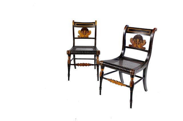 Pair of black fancy chairs with gold stenciling: A rectangular gilt design decorates the crest rail and stiles. The splat is adorned with opposing swans. The turned front legs and front stretcher are decorated with gilt foliage and are nicely turned
