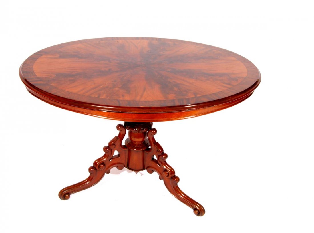 Ovaler Louis Philippe Salontisch: Norddeutsch um 1870. Auf drei geschnitzten Volutenfüßen balusterförmiger kannelierter Mittelschaft, breite gerade Zarge, überkragende Tischplatte. Mahagoni. H.: 71 cm, Br.: 110 cm, T.: 85 cm.