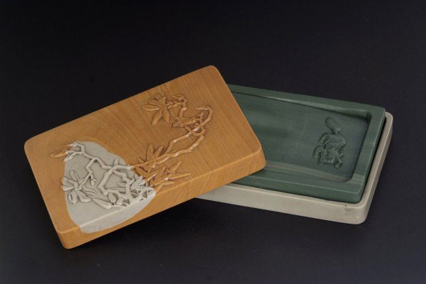 A Finely Carved Inkstone: The inkstone is made of rare stone from Songjiang river of north China, well-carved with a mystical beast at the well, the stone of green tone with white strikes, carved stone case. Length:4.75, Width