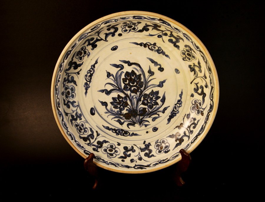 Blue & White Plate: A circular dish; its design features the entirety of the front of the plate being painted, with the plate depicting a scene between five people and the border having a floral pattern; a seal may be fo