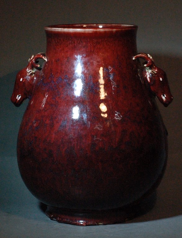 Large Ox Blood Red Vase: Large Ox Blood Red Vase that is circular at any cross-section; the handles are carvings of the head of a deer. ex-collection from a local collection during 1980's. Size: D14" H 15" Starting Bid: 350