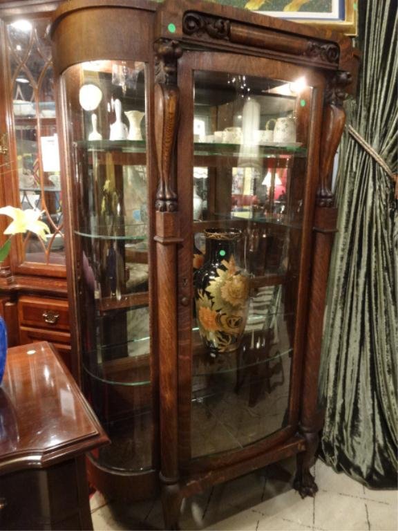 ANTIQUE DARK OAK DISPLAY CABINET, CENTRAL GLAZED FULL: ANTIQUE DARK OAK DISPLAY CABINET, CENTRAL GLAZED FULL LENGTH DOOR FLANKED BY LION CARVED PILASTERS, CONVEX GLAZED SIDE PANELS, RAISED ON PAW FEET, MIRRORED BACK, GLASS SHELVES, LIGHTED, APPROX 6'H X 4