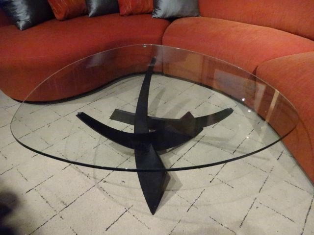 MODERN METAL AND GLASS COFFEE TABLE, CURVED TRIANGULAR: MODERN METAL AND GLASS COFFEE TABLE, CURVED TRIANGULAR GLASS TOP, BLACK METAL BASE, EXCELLENT CONDITION GENTLY USED, APPROX 3.5'W X 20"H