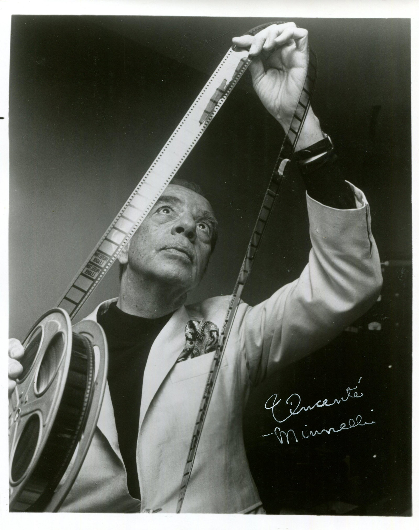 MINNELLI VINCENTE: (1903-1986): MINNELLI VINCENTE: (1903-1986) American film and stage director, Academy Award winner. A good signed 8 x 10 photograph of Minnelli standing in a half-length pose looking upwards as he inspects a reel