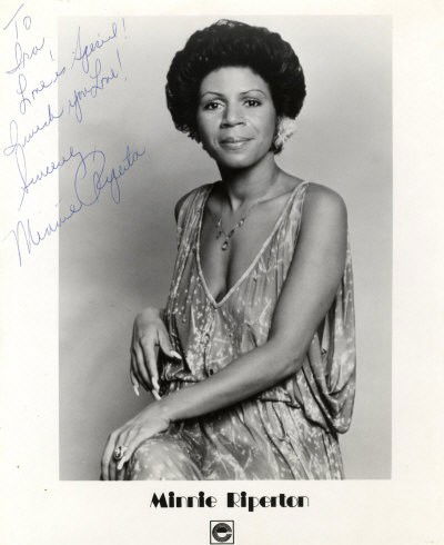 RIPERTON MINNIE: (1947-1979) American Singer & Son: RIPERTON MINNIE: (1947-1979) American Singer & Songwriter remembered for her single Lovin' You (1975). Scarce signed and inscribed 8 x 10 photograph of Riperton seated in a three quarter length pose.