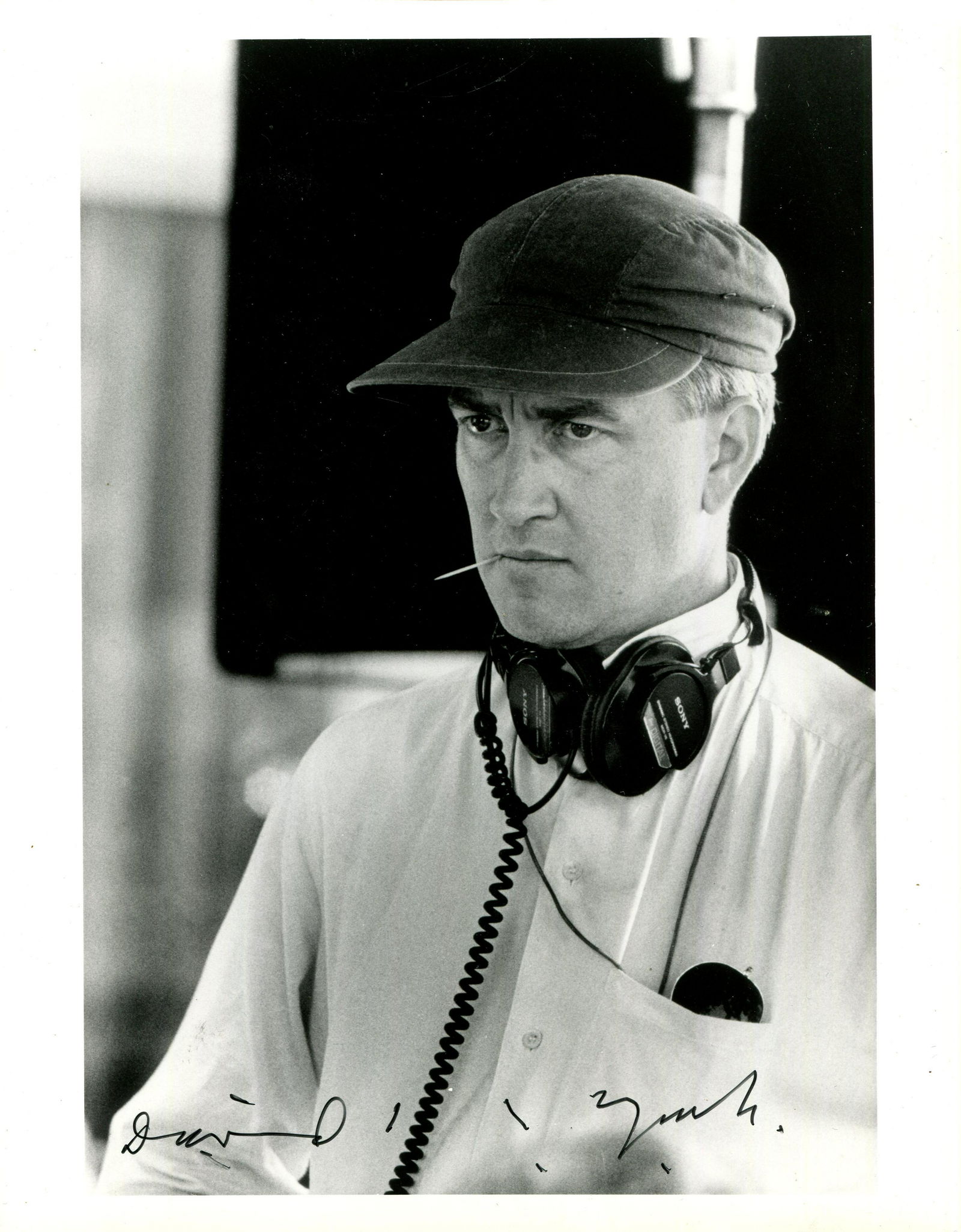 WILD AT HEART:: WILD AT HEART: David Lynch (1946- ) American film director. Signed 8 x 10 photograph of Lynch in a head and shoulders pose wearing a set of headphones around his neck and with a toothpick in his mouth