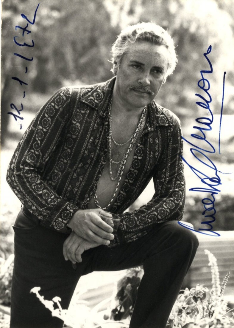 DEL MONACO MARIO: (1915-1982) Italian Tenor. Signe: DEL MONACO MARIO: (1915-1982) Italian Tenor. Signed 4 x 6 postcard photograph of the singer standing outdoors in a three quarter length pose holding a drink in one hand. Signed in bold blue fountain p