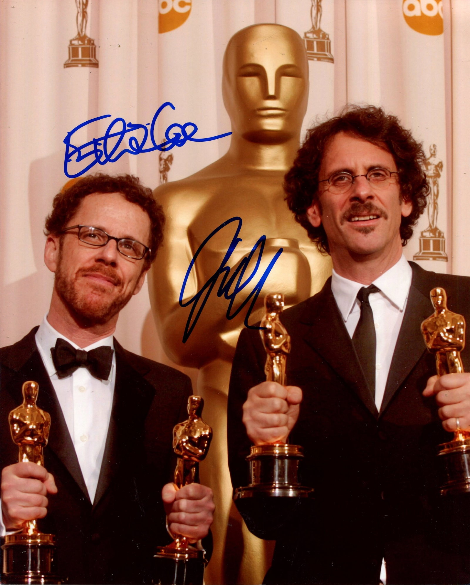 COEN BROHERS:: COEN BROHERS: Signed colour 8 x 10 photograph by both Joel Coen (1954- ) and Ethan Coen (1957- ) individually, the image depicting the American sibling film directors standing in half-length poses