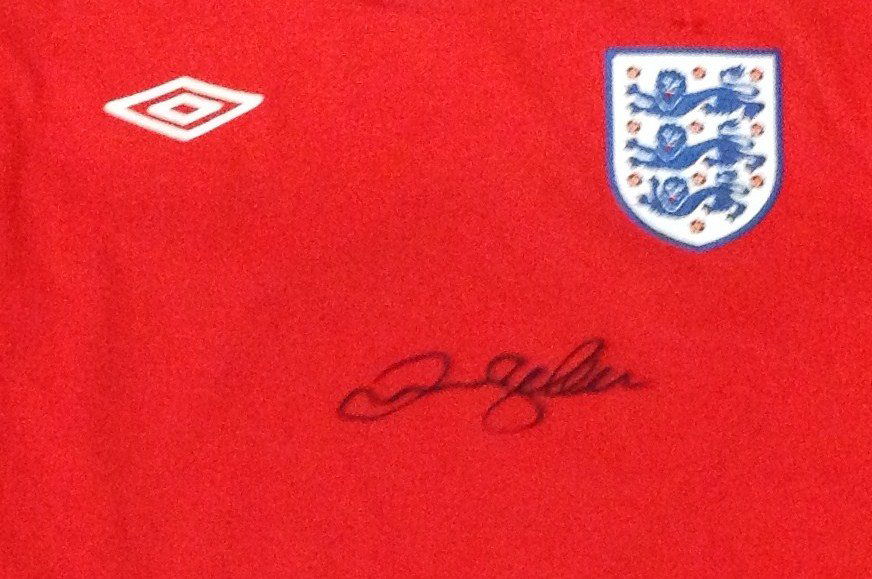 BECKHAM DAVID: (1975- ) English Footballer. A r: BECKHAM DAVID: (1975- ) English Footballer. A red official souvenir Umbro England long sleeved football jersey, signed by Beckham in bold black ink with his name alone. VG