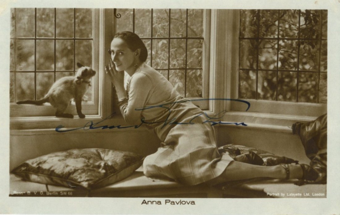 PAVLOVA ANNA: (1881-1931) Russian Ballet Dancer. A: PAVLOVA ANNA: (1881-1931) Russian Ballet Dancer. A fine vintage signed sepia postcard photograph, the image showing Pavlova seated in a full length pose at a window, with a small cat at her side. Sign