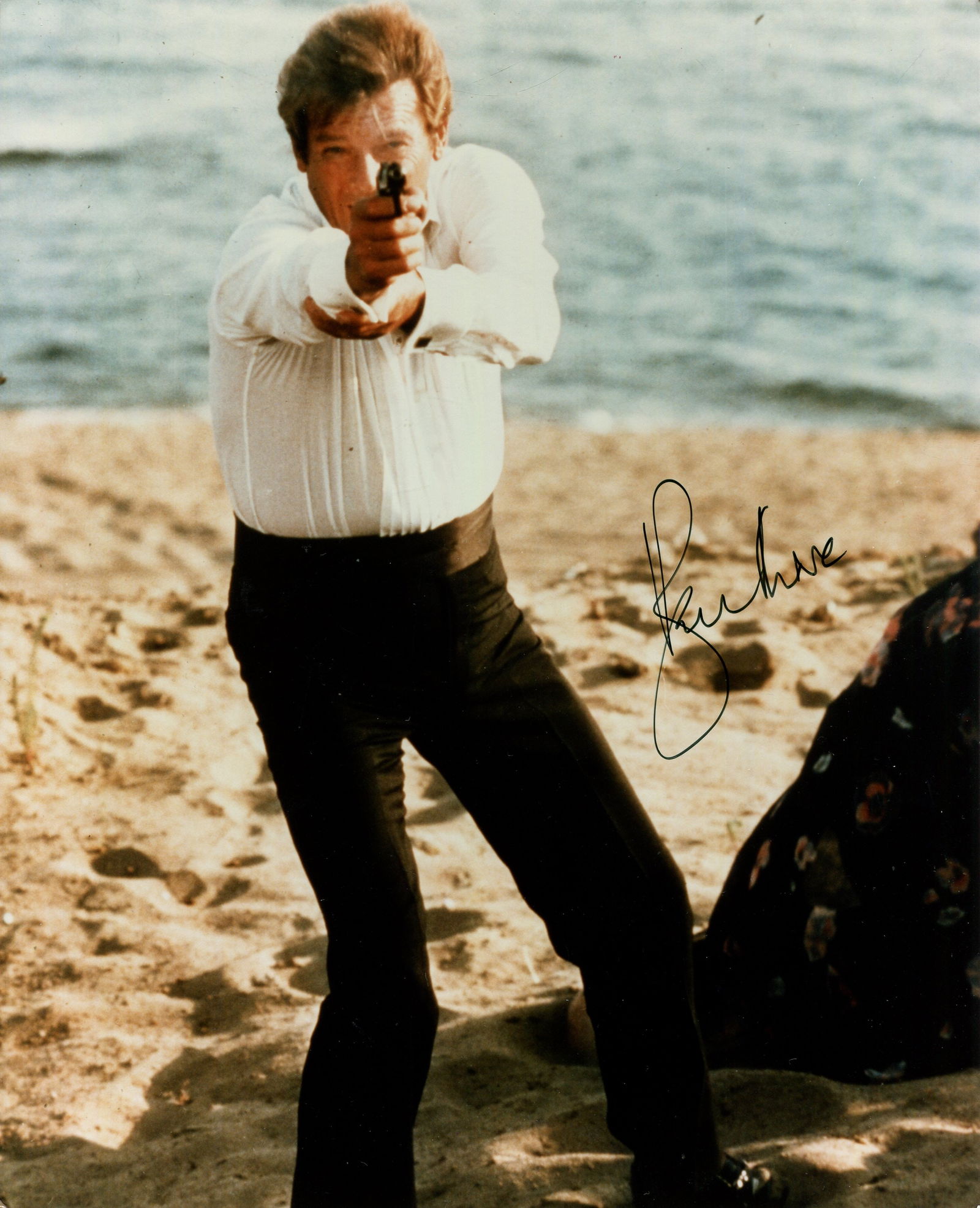 MOORE ROGER: (1927-2017): MOORE ROGER: (1927-2017) English actor, famous for his portrayal of the fictional British secret agent James Bond in seven films from 1973-85. Signed colour 8 x 10 photograph of Moore standing in a fu