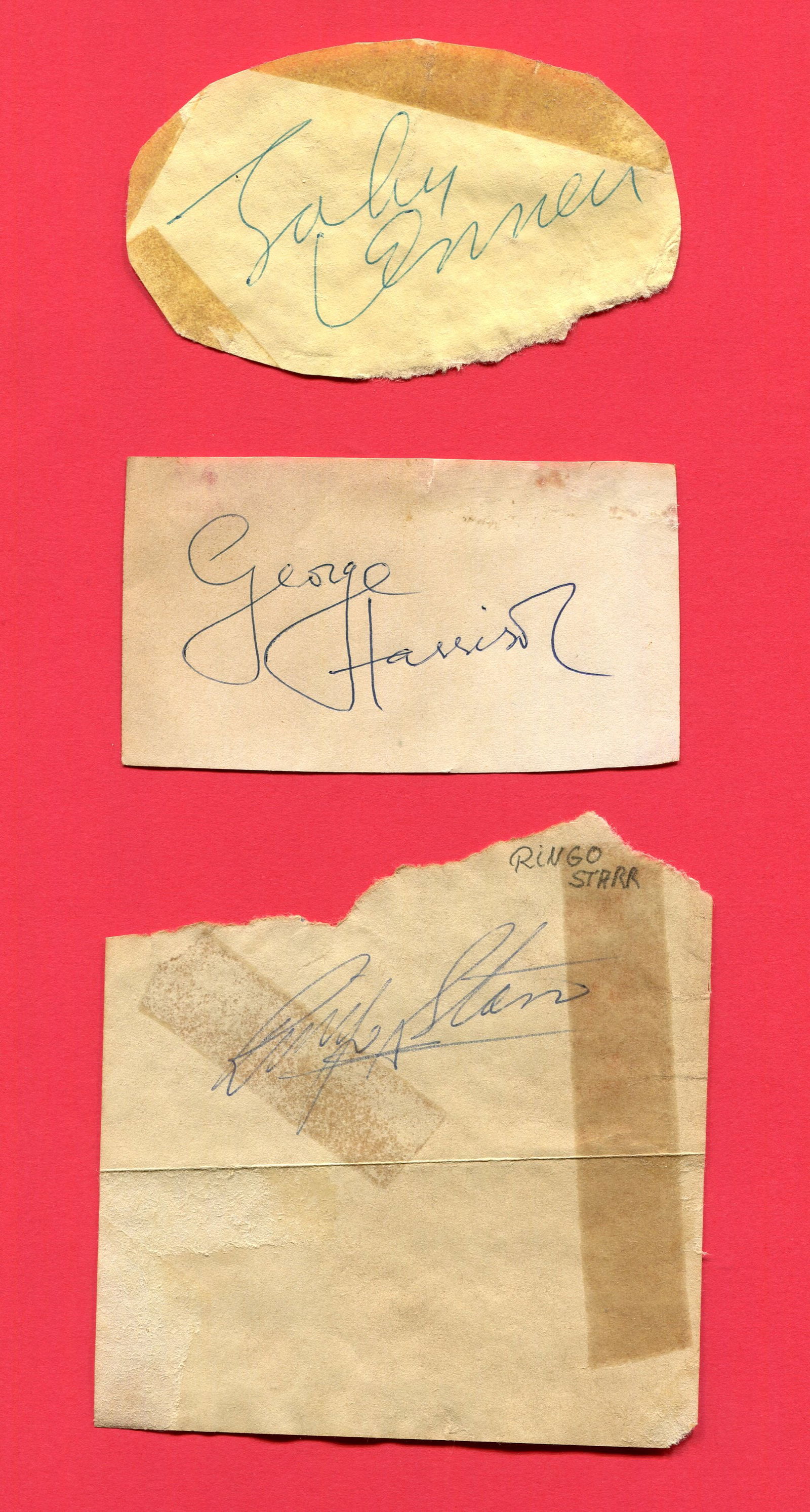 BEATLES THE:: BEATLES THE: Individual ink signatures by three band members of the Beatles, comprising John Lennon, George Harrison and Ringo Starr, each on irregularly clipped or torn 12mo pieces. Some tape stainin