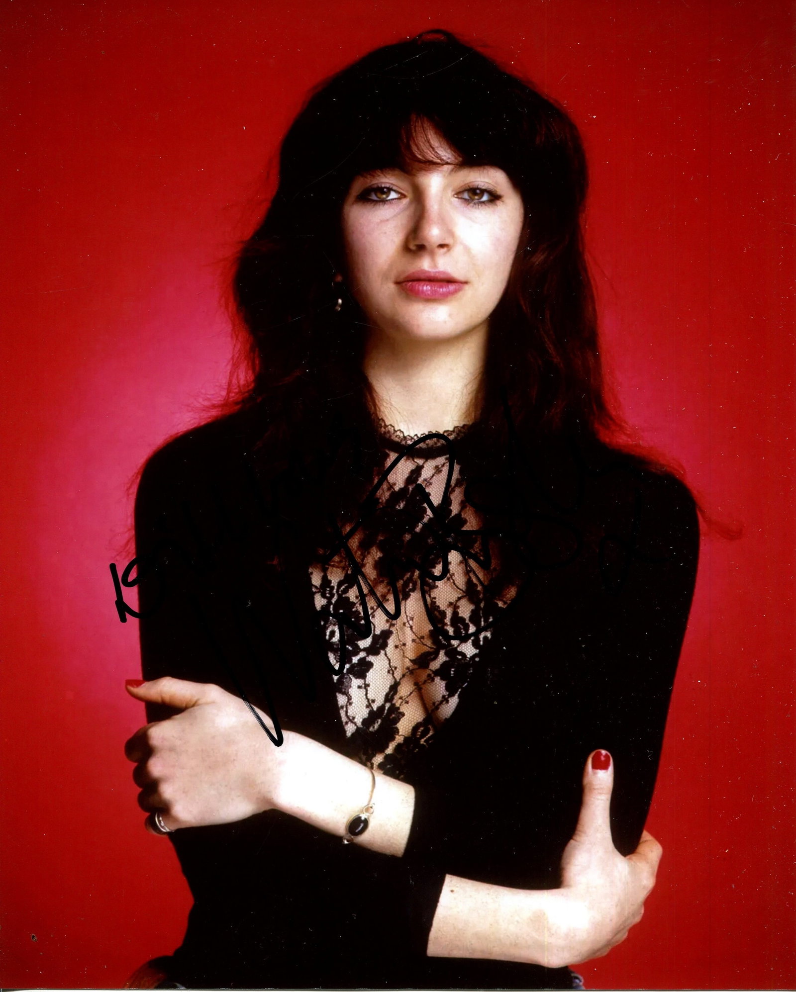 BUSH KATE: (1958- ): BUSH KATE: (1958- ) English singer and songwriter. Signed colour 8 x 10 photograph of Bush standing in a half-length pose with her arms folded. Signed in black ink, largely across a darker area at the