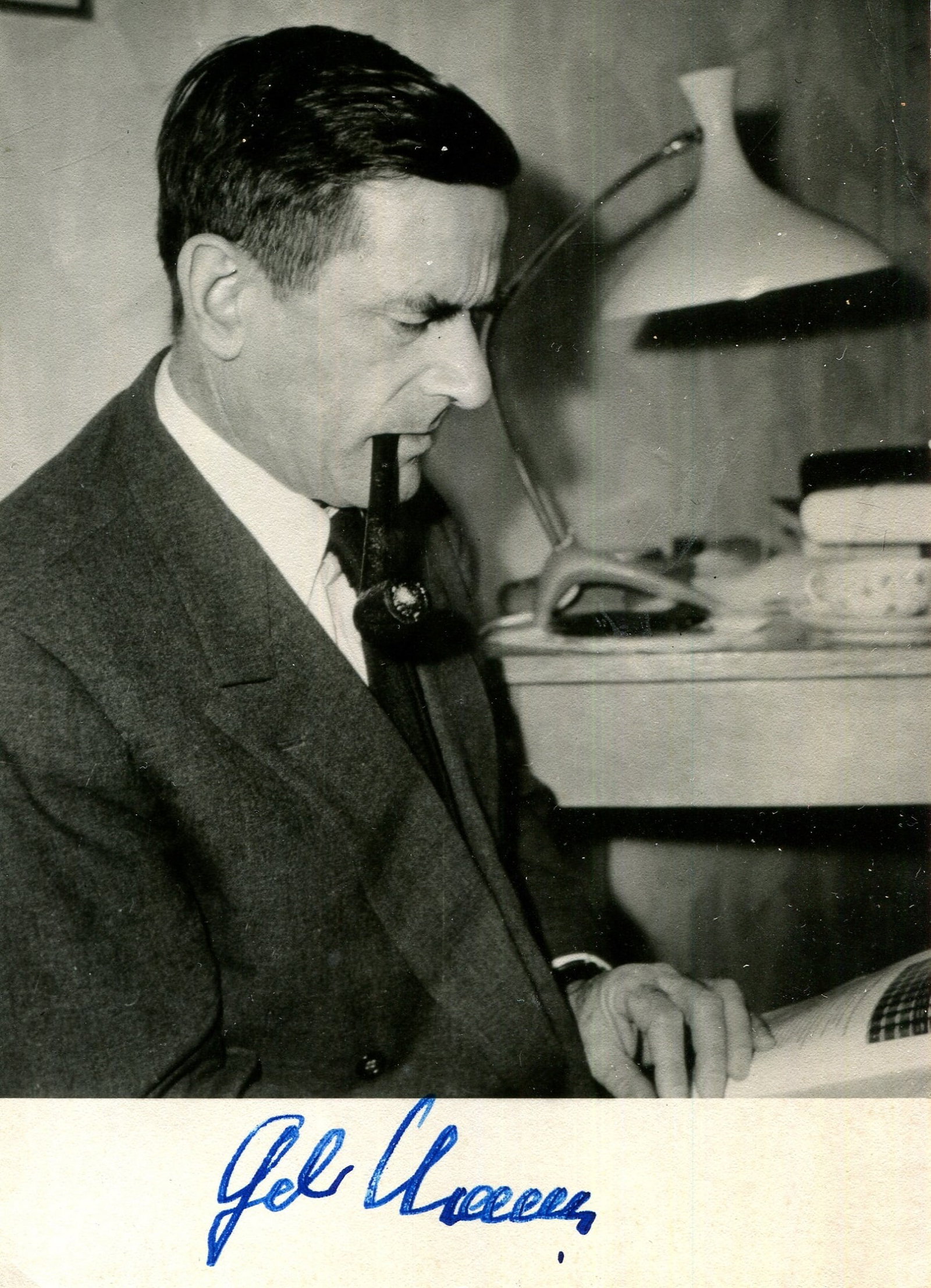 MANN GOLO: (1909-1994): MANN GOLO: (1909-1994) German historian and essayist, the son of Nobel Laureate Thomas Mann. Vintage signed 4 x 6 photograph of Mann in a profile half-length pose smoking a pipe and reading a publicat