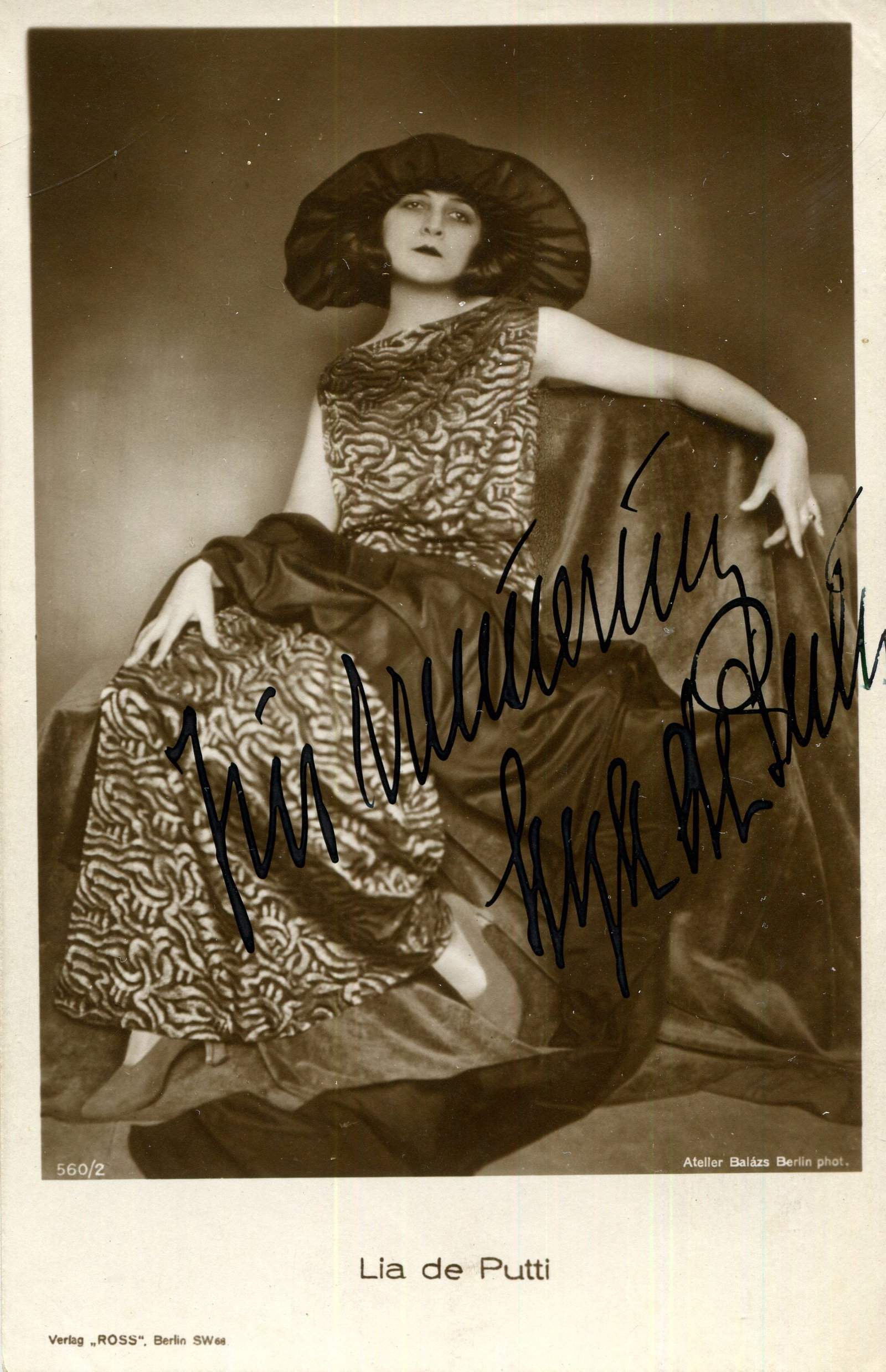 DE PUTTI LYA: (1897-1931): DE PUTTI LYA: (1897-1931) Hungarian actress of the silent era, noted for her portrayals of vamp characters. Scarce vintage signed sepia postcard photograph of the actress seated in a full-length