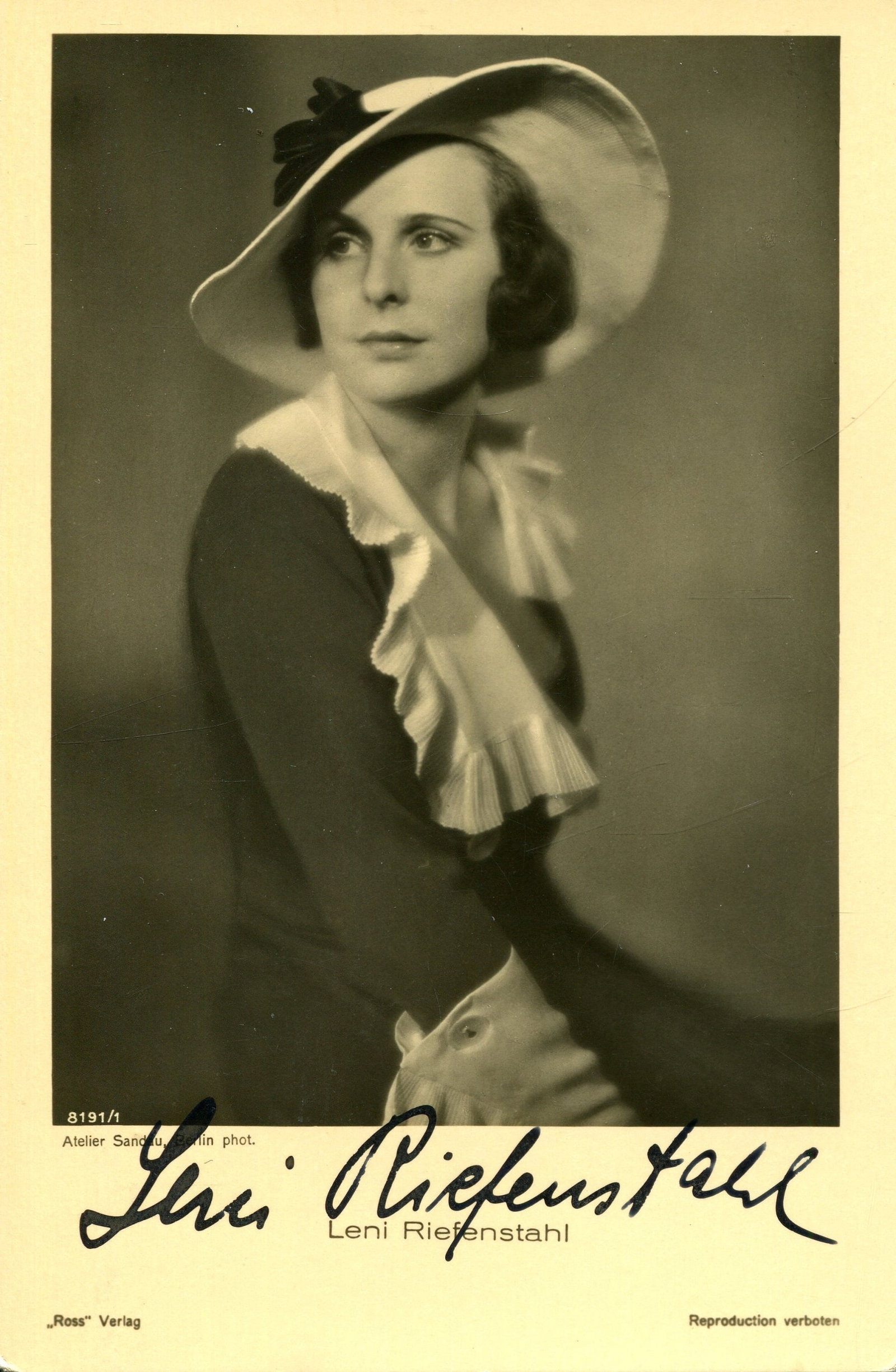 RIEFENSTAHL LENI: (1902-2003): RIEFENSTAHL LENI: (1902-2003) German film director, known for her role in producing Nazi propaganda. Vintage signed sepia 3.5 x 5.5 postcard photograph of Riefenstahl seated in an elegant