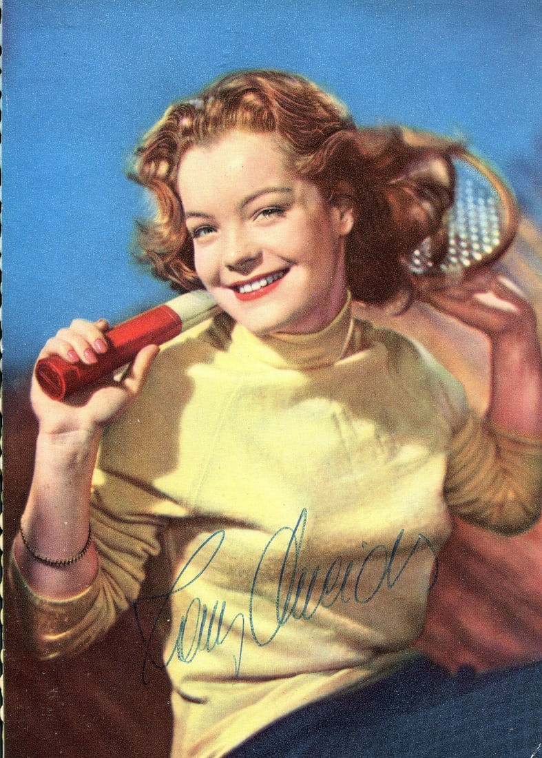 SCHNEIDER ROMY: (1938-1982): SCHNEIDER ROMY: (1938-1982) German-French actress. Vintage signed colour 4 x 5.5 postcard photograph of the young actress in a happy three-quarter length pose and holding a sports racket behind her