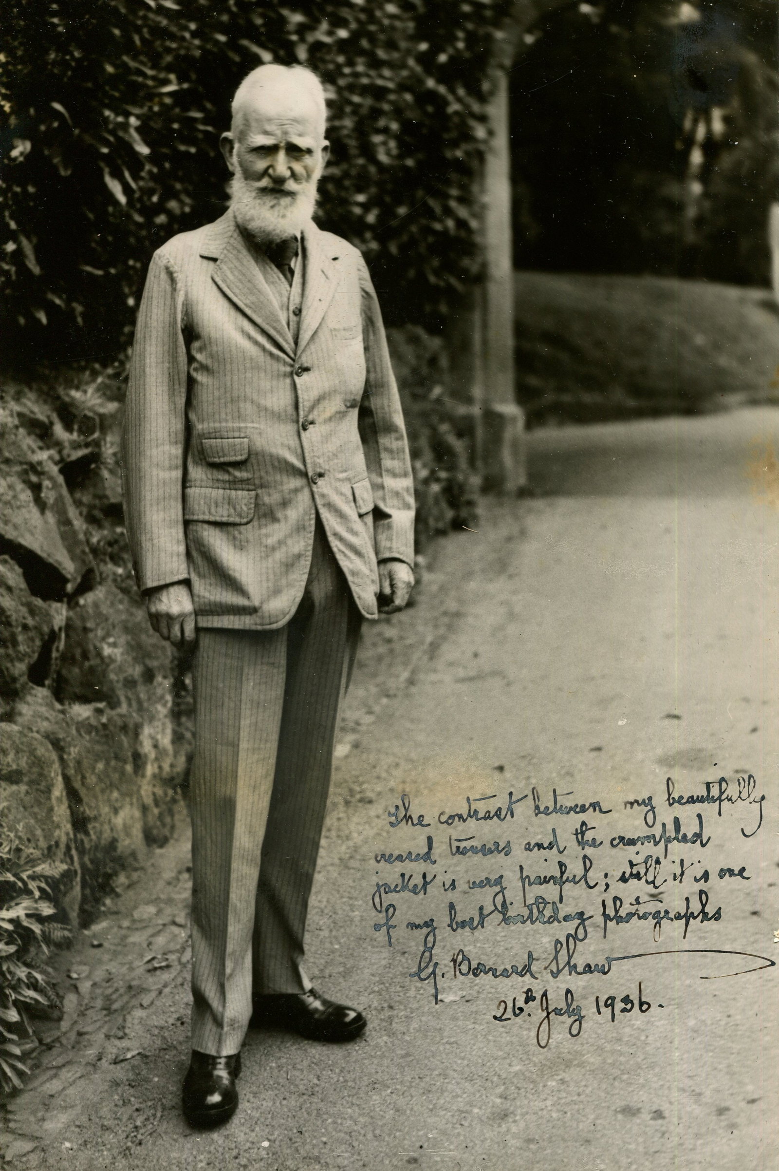 SHAW GEORGE BERNARD: (1856-1950) Signed on his 80th Birthday: SHAW GEORGE BERNARD: (1856-1950) Irish playwright, Nobel Prize winner for Literature, 1925. An excellent vintage signed 6 x 9.5 photograph of Shaw standing outdoors in a full-length pose wearing a lig