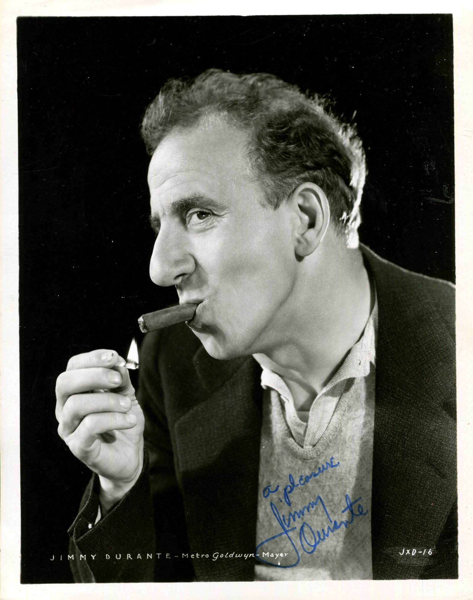 DURANTE JIMMY: (1893-1980): DURANTE JIMMY: (1893-1980) American actor and comedian. Signed 8 x 10 photograph of Durante in a profile head and shoulders pose lighting a cigar with a match. Signed in blue ink to a lighter area at