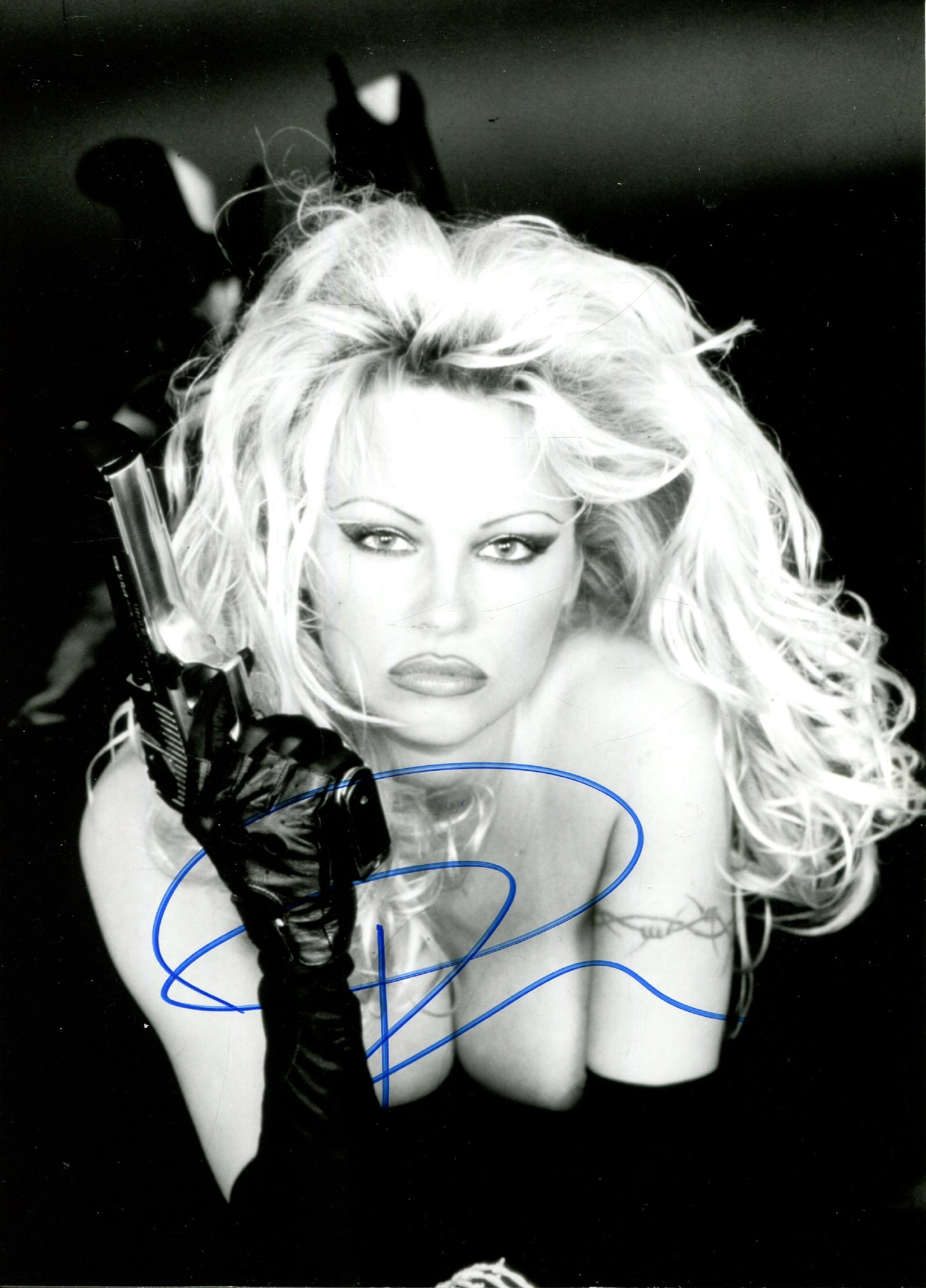 ANDERSON PAMELA: (1967- ): ANDERSON PAMELA: (1967- ) Canadian-American actress and model. Signed 5 x 7 photograph of Anderson, the image depicting her in a sensual topless pose, with a revolver in hand. Signed in bold blue ink
