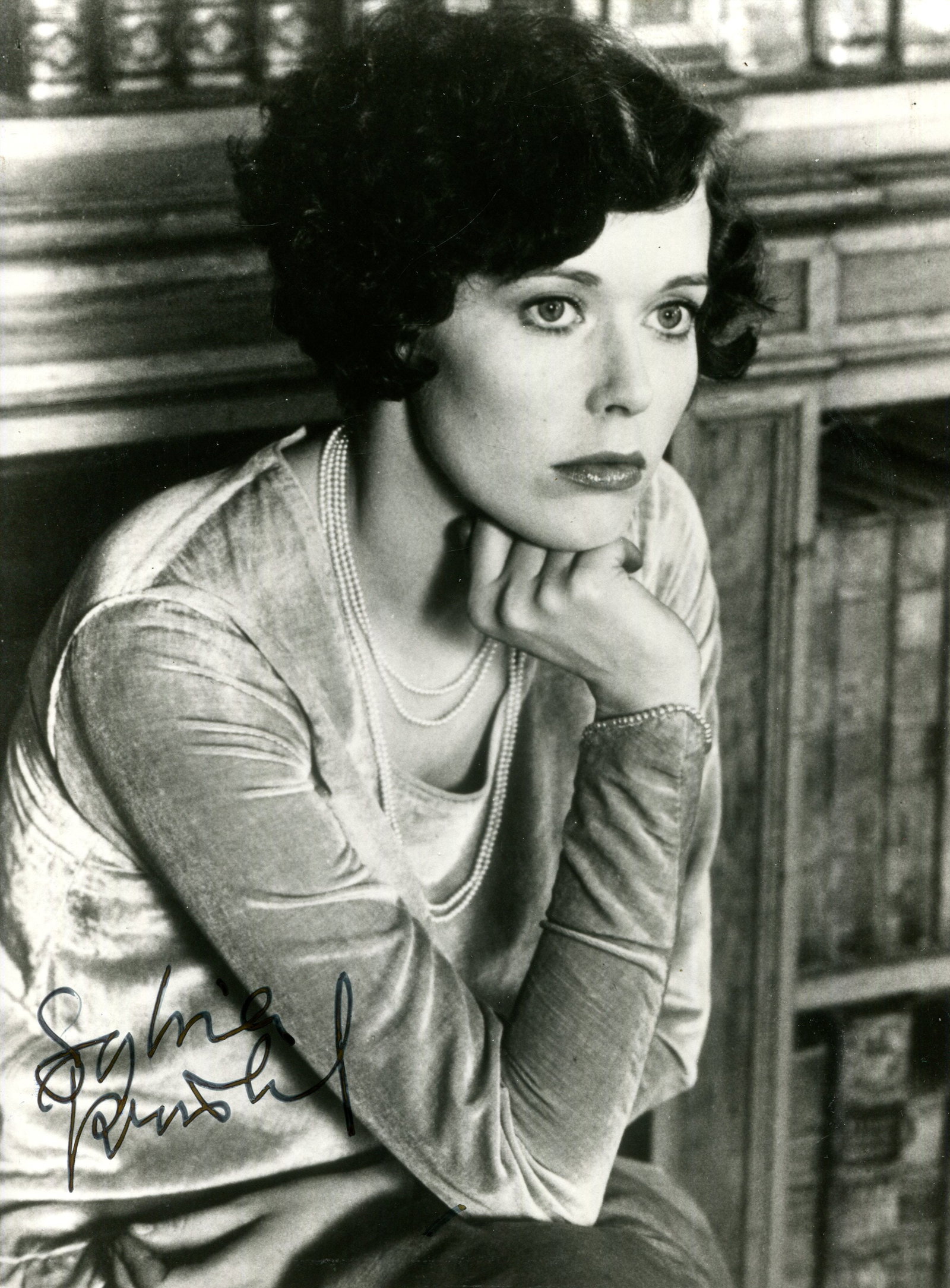 KRISTEL SYLVIA: (1952-2012): KRISTEL SYLVIA: (1952-2012) Dutch actress and model, famous for her performance in the title role of the French erotic drama film Emmanuelle (1974). Signed 7 x 9.5 photograph of Kristel seated in a